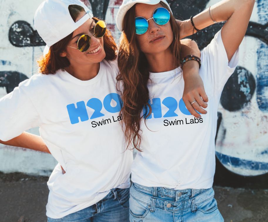 2 women standing in front of a wall wearing H2Q branded T-shirts